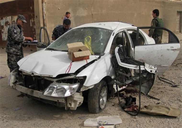 Iraqi security forces inspect a damaged car at a bombing site in Baghdad, Iraq on Monday, Oct. 4. 2010. Police officials say a roadside bombing has targeted the convoy of a deputy minister in Iraq's government, killing and injuring several people.